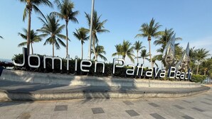 A paved area with a sign reading 'Jomtani Pattaya Beach' surrounded by palm trees. - Sleep Owl Jomtien (Pattaya)