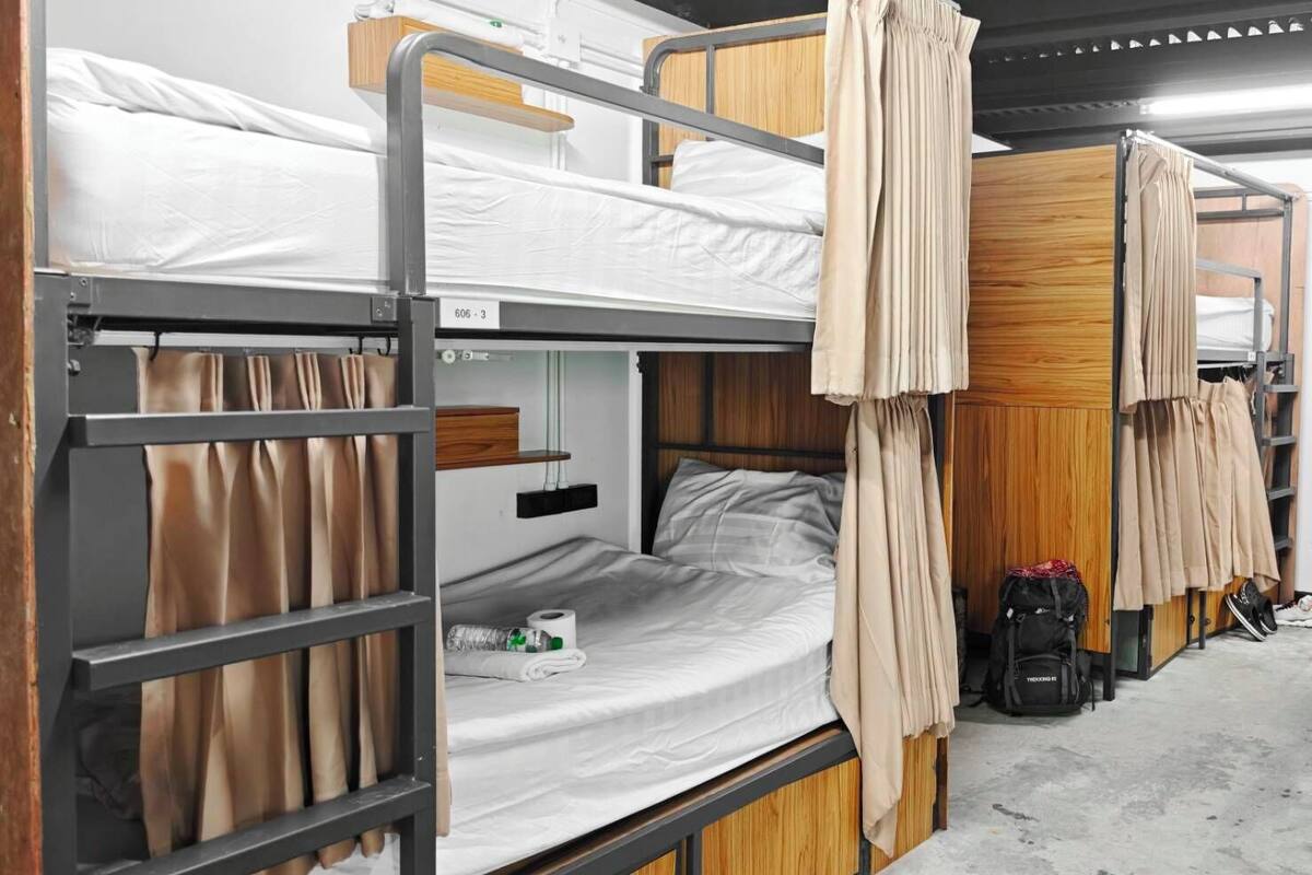 A bunk bed room with a wooden headboard, a small shelf, and a suitcase on the floor.