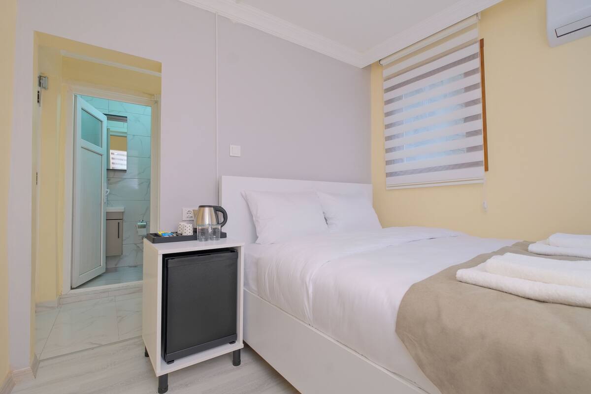 A hotel room with a bed, bedside table, and a small cabinet.