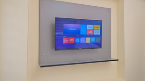 A flat-screen TV mounted on a wall with a shelf below it. - Lucky Hotel İstanbul (Istanbul)