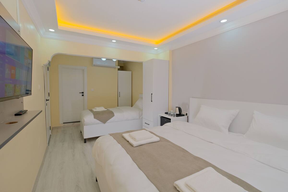 A hotel room with a large bed, a smaller bed, a desk, and a TV.