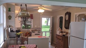 A kitchen with a dining table, chairs, a refrigerator, a stove, and a window. - Classic Green Lake cottage, lakefront, screened boathouse deck, dock, swimming (Markesan)