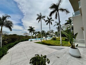 Un resort con piscina, palmeras y un paseo pavimentado.
