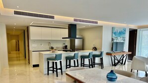 A modern kitchen with a central island, bar stools, and a dining area with a marble table. - Park Life Bolongo (Bucerías)