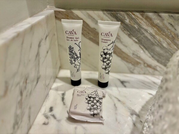 A bathroom with marble walls, containing three CAVA products: Shower Gel, Shampoo, and Bar Soap. - Park Life Bolongo (Bucerías)