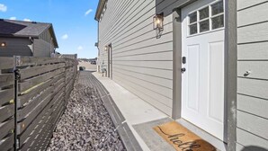 A narrow pathway leading to a building with a white door and a 'hello' mat. - Private Caldwell Guesthouse w/ King Bed, Balcony & Kitchenette (Caldwell)