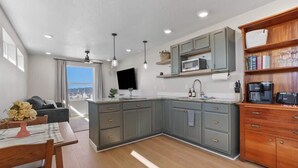 A modern kitchen with grey cabinets, a wooden dining table, and a view to the outside. - Private Caldwell Guesthouse w/ King Bed, Balcony & Kitchenette (Caldwell)