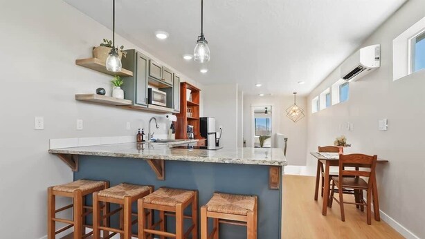 A modern kitchen with a marble countertop, wooden stools, and pendant lighting. - Private Caldwell Guesthouse w/ King Bed, Balcony & Kitchenette (Caldwell)