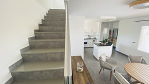 A modern kitchen with white cabinets, a central island, and a dining area with a wooden table and chairs. - Modern Villa 6 pax, private pool, countryside views, free wifi (Binibeca)