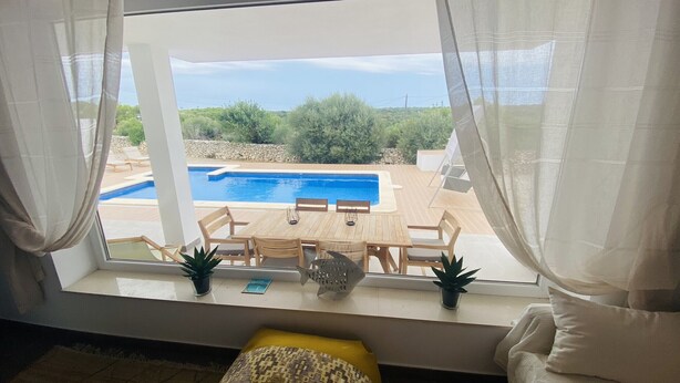 A room with a view of a pool, wooden furniture, and potted plants. - Modern Villa 6 pax, private pool, countryside views, free wifi (Binibeca)