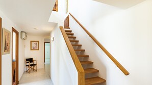 Un escalier avec des marches en bois et une rampe, menant à l’étage supérieur.