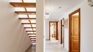 Un couloir avec des poutres en bois, un sol carrelé et des portes en bois.