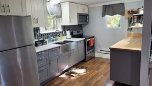 A modern kitchen with stainless steel appliances, grey cabinets, and a wooden floor.