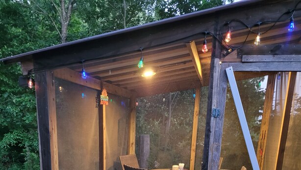 A wooden structure with a covered patio area, a table with chairs, and a window.