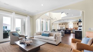 A spacious living room with a large sofa, a coffee table, and a view of the kitchen and dining area.
