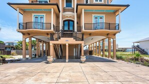 A multi-story house with a central staircase, large windows, and a covered patio area.