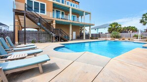 A two-story building with a swimming pool, outdoor seating, and a covered patio area.