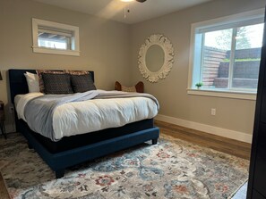 A bedroom with a bed, a window, a mirror, and a patterned rug. - Charming 1 bed/bath Suite in waterfront Cottage (Somers)
