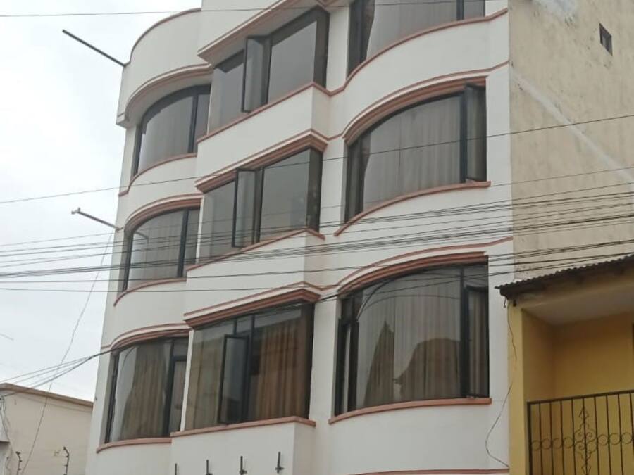 Un edificio de varios pisos con fachada plana, amplias ventanas y un cartel de hotel visible.
