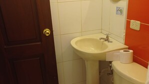 A bathroom with a toilet, sink, and mirror.