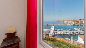 Una habitación con un ventanal grande que da a un puerto deportivo con barcos y un edificio rojo.