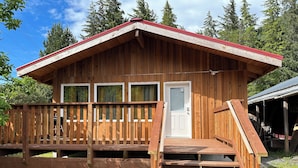 Une cabane en bois dotée d’un porche et d’un escalier menant à l’entrée.