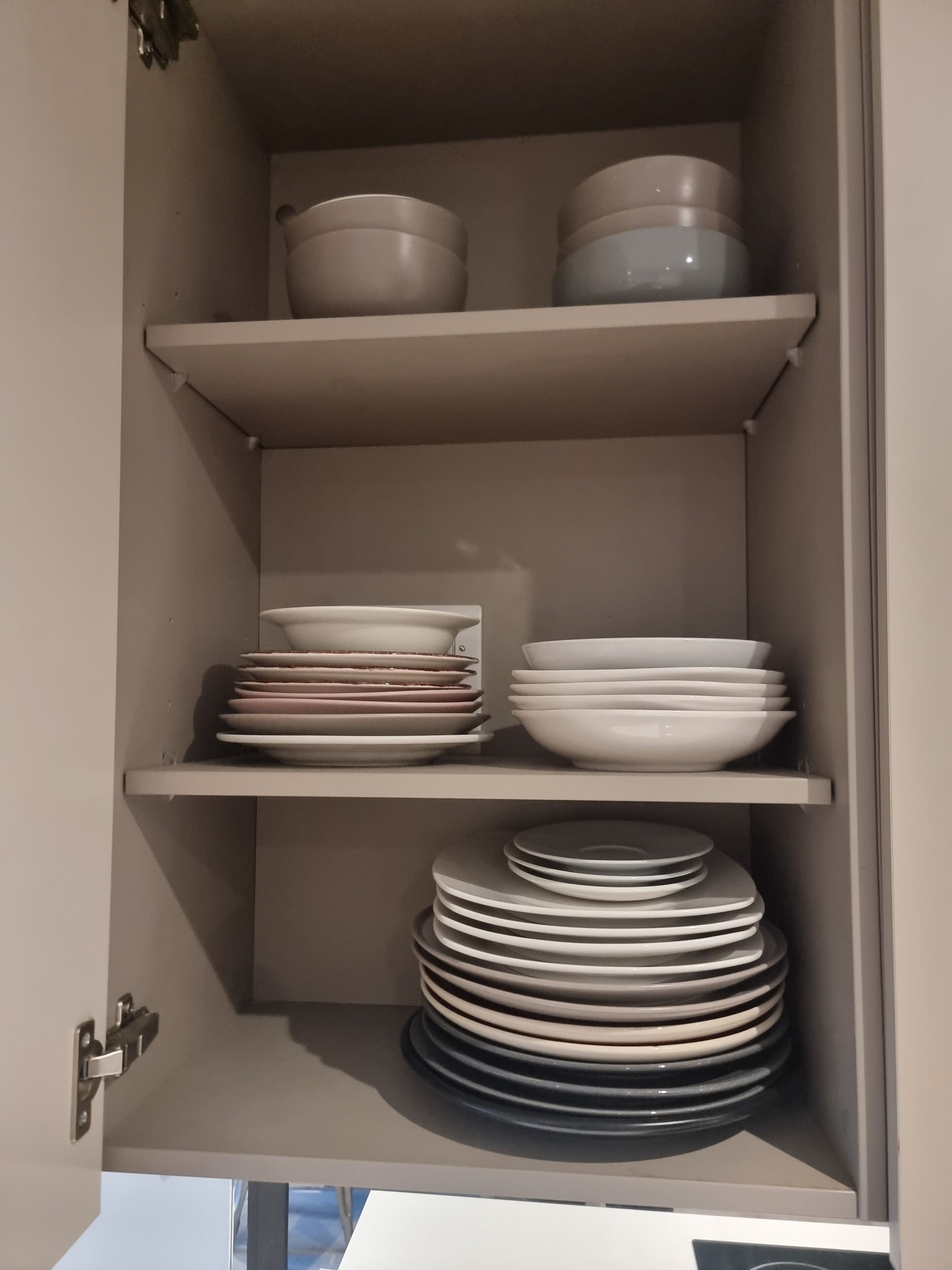 A cabinet with shelves holding plates and bowls.