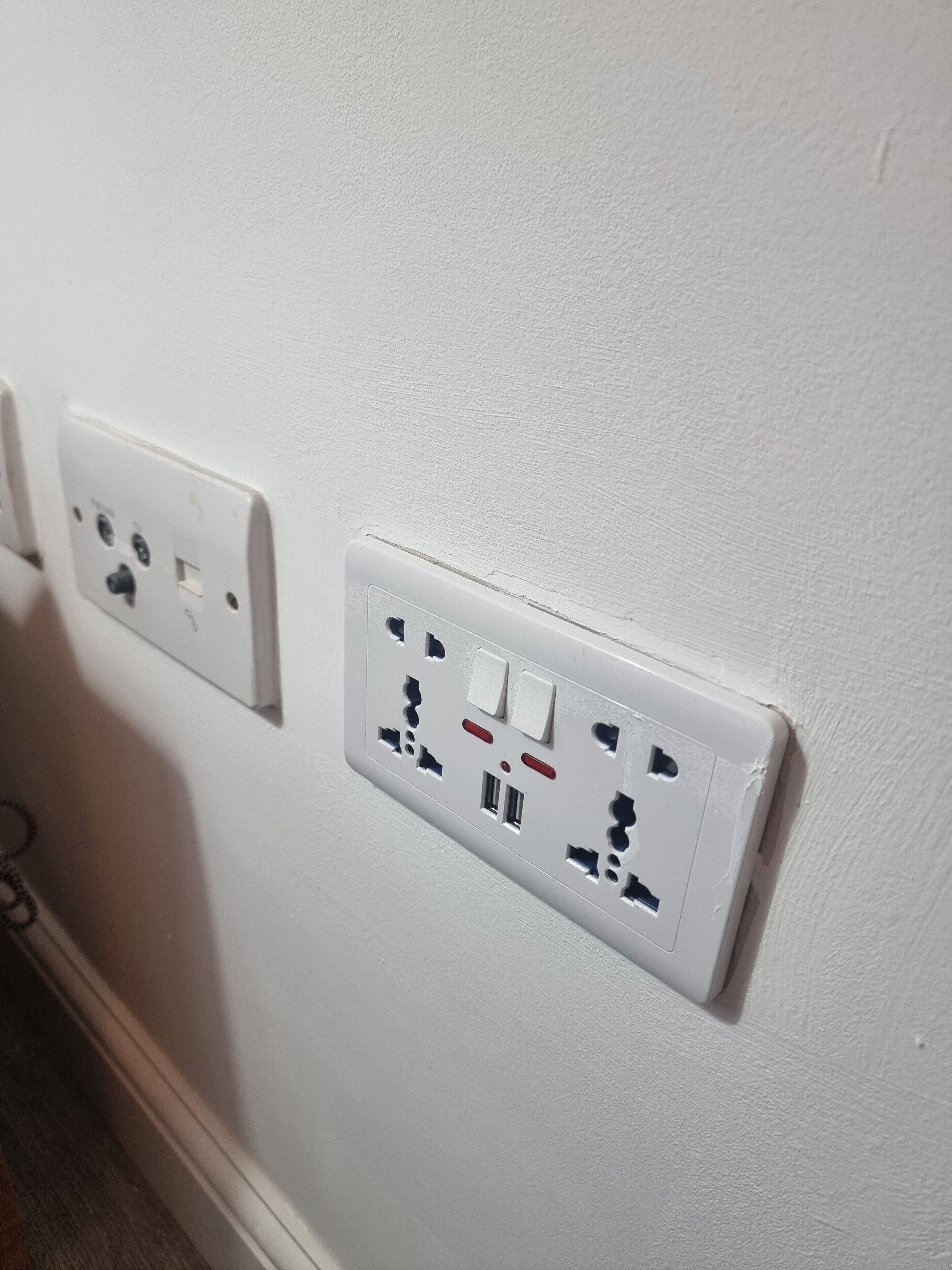 A white wall with two electrical outlets, one with a switch and the other with USB ports.