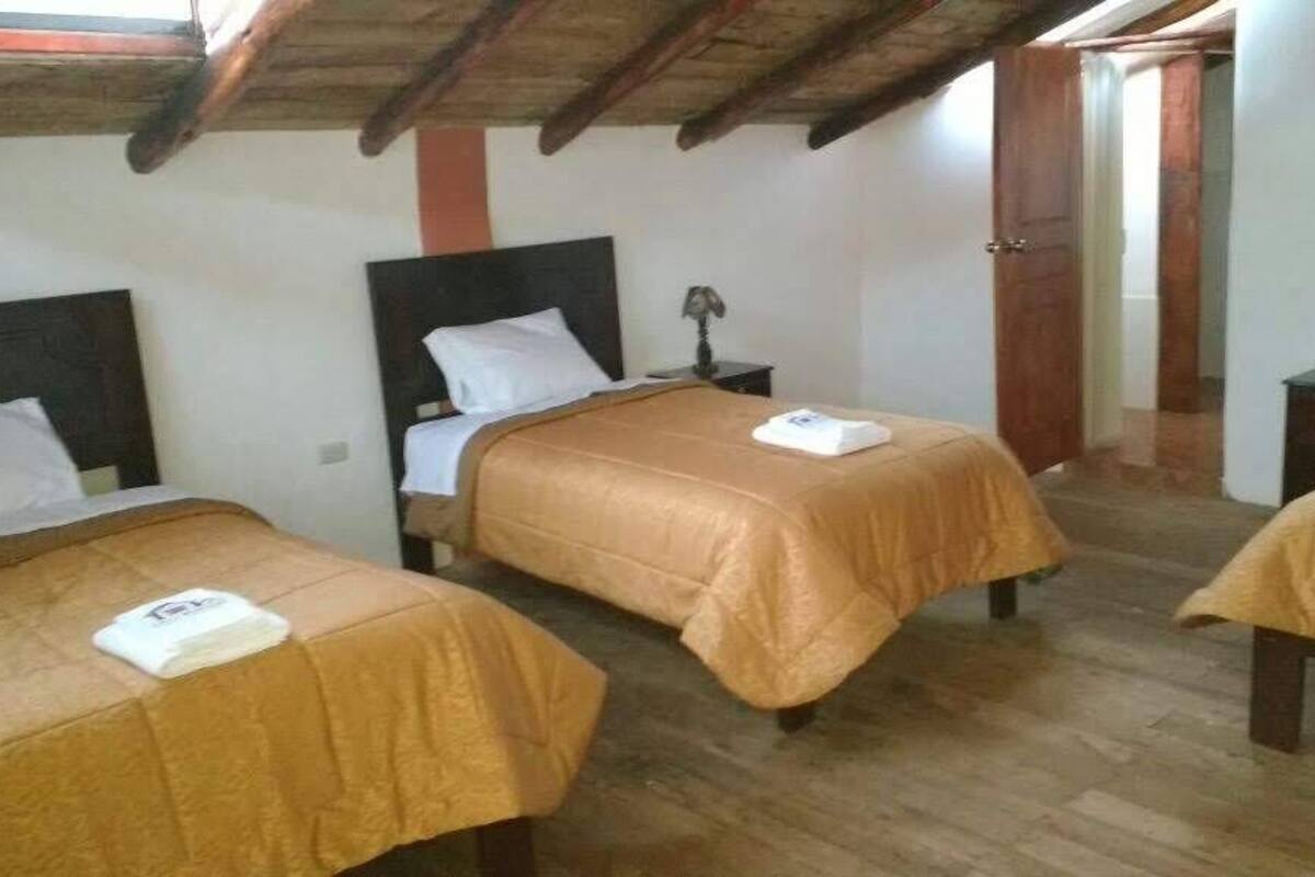 A room with three single beds, wooden headboards, and a wooden ceiling.