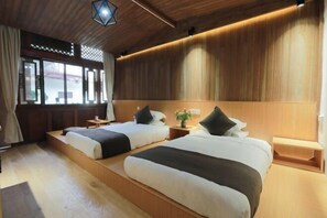 A hotel room with two beds, wooden paneling, a window with curtains, and a small table with a plant. - Xiangxingli Inn (Tengchong Heshun Ancient Town Branch) (Tengchong)