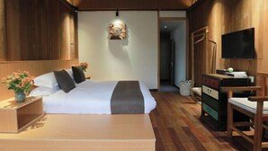 A bedroom with a bed, bedside table with flowers, a dresser, a chair, a television, and a wall-mounted artwork. - Xiangxingli Inn (Tengchong Heshun Ancient Town Branch) (Tengchong)