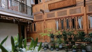 A courtyard with wooden buildings, potted plants, and a sign with Chinese characters. - Xiangxingli Inn (Tengchong Heshun Ancient Town Branch) (Tengchong)