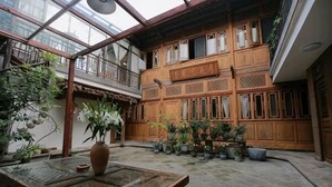 A courtyard with wooden buildings, potted plants, and a glass table. - Xiangxingli Inn (Tengchong Heshun Ancient Town Branch) (Tengchong)