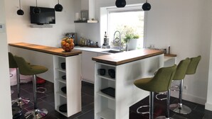 Una cocina moderna con una isla central, taburetes de bar e iluminación colgante.