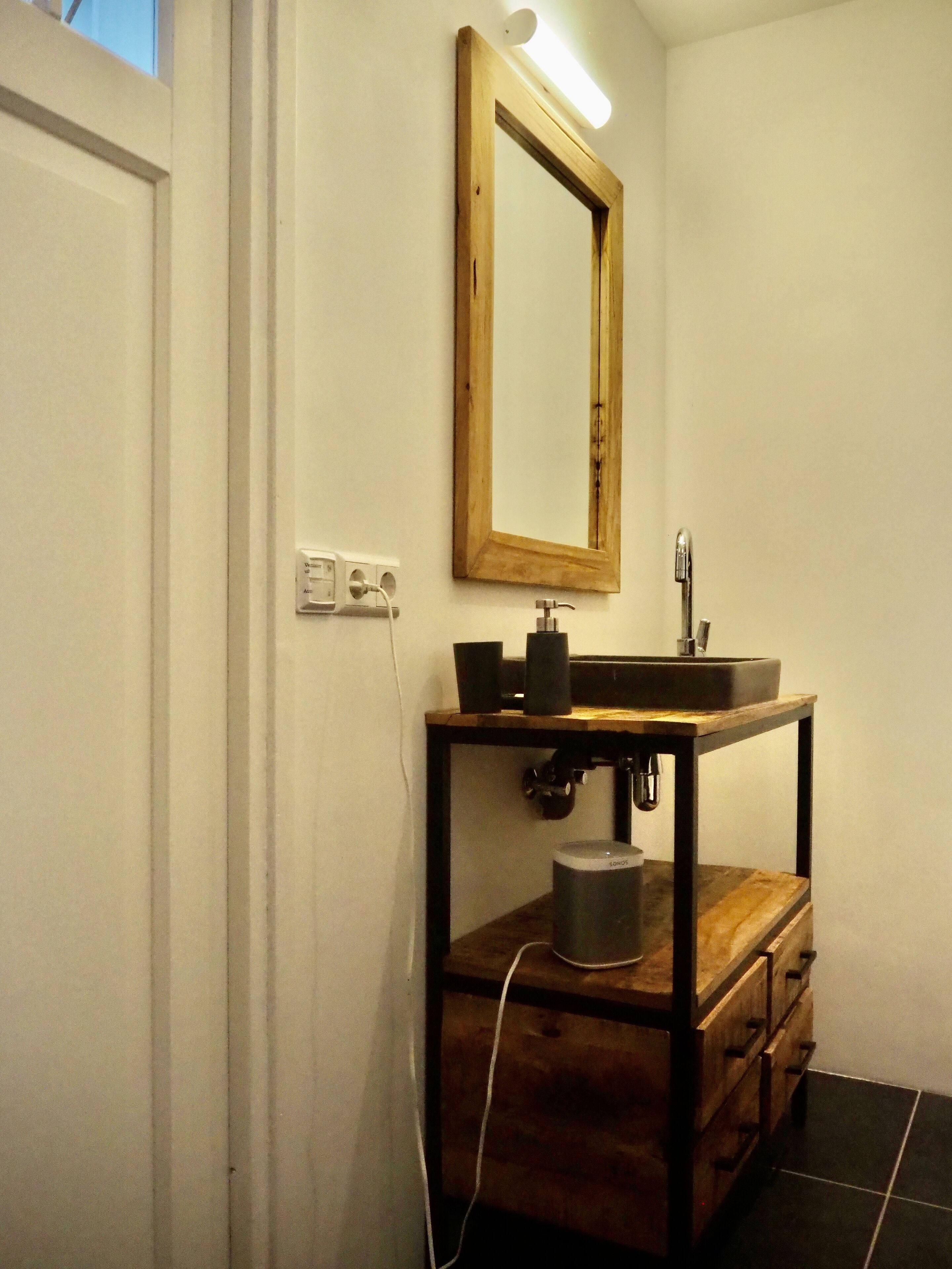 Une salle de bain avec un meuble-lavabo en bois, un miroir, un évier et des toilettes.