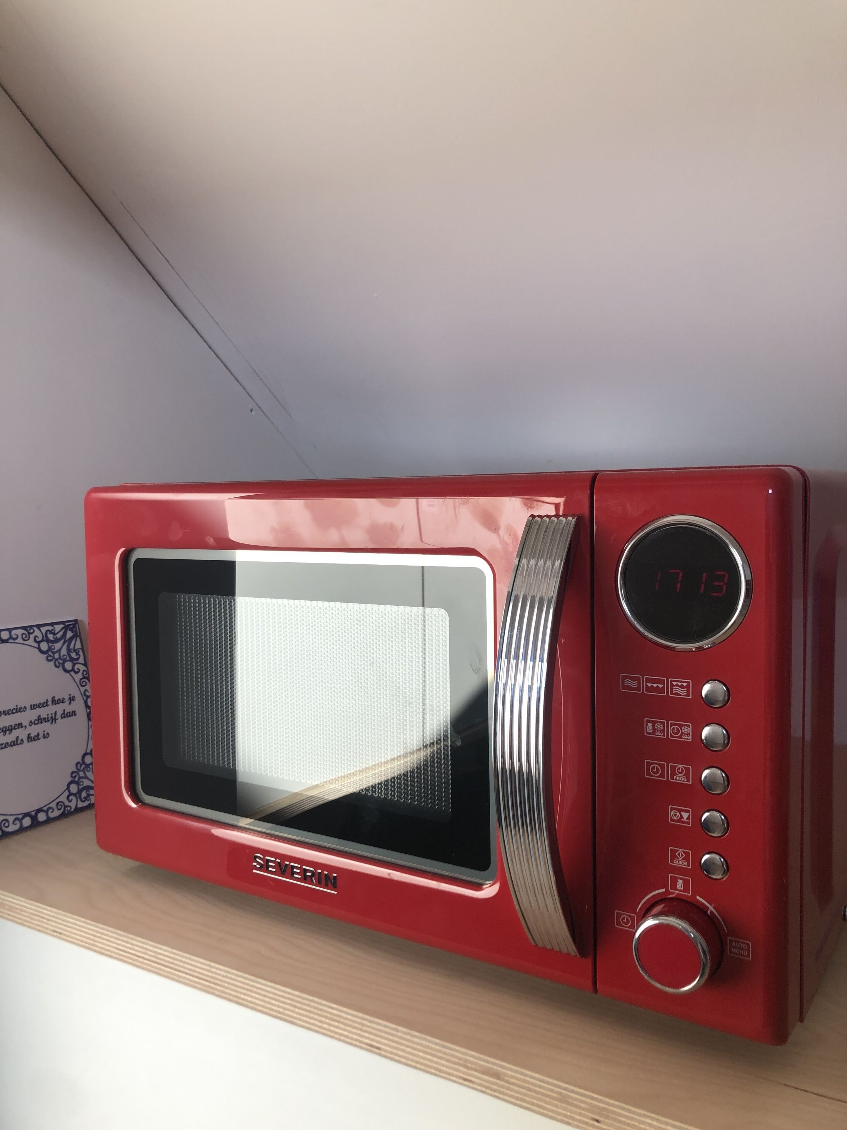 Een rode magnetron met een digitaal display aan de rechterkant.