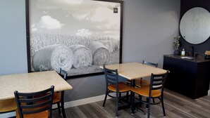 A room with a large framed picture of hay bales, a round mirror, and a small reception desk with a vase of flowers.