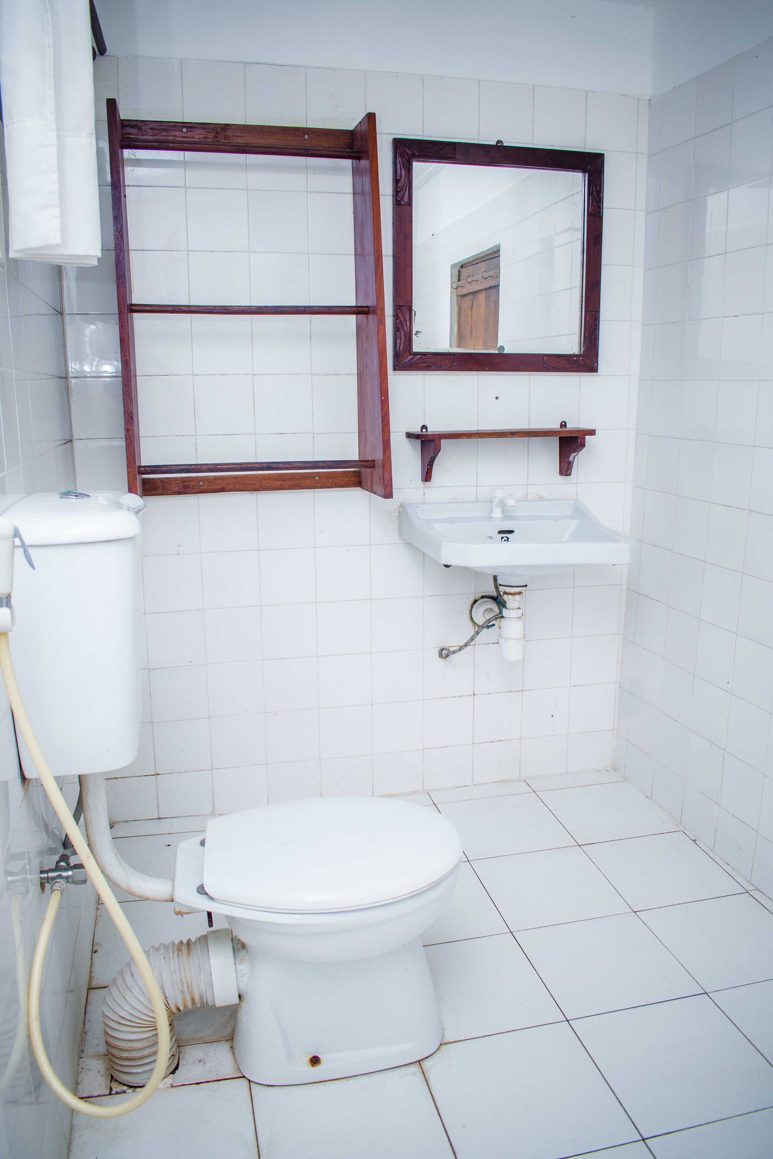 A bathroom with a toilet, a sink, and a mirror.