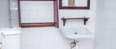 A bathroom with a toilet, a sink, and a mirror.