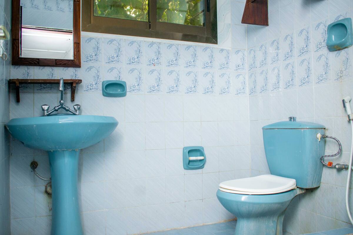Un baño con lavamanos, inodoro y azulejos azules con motivos florales.