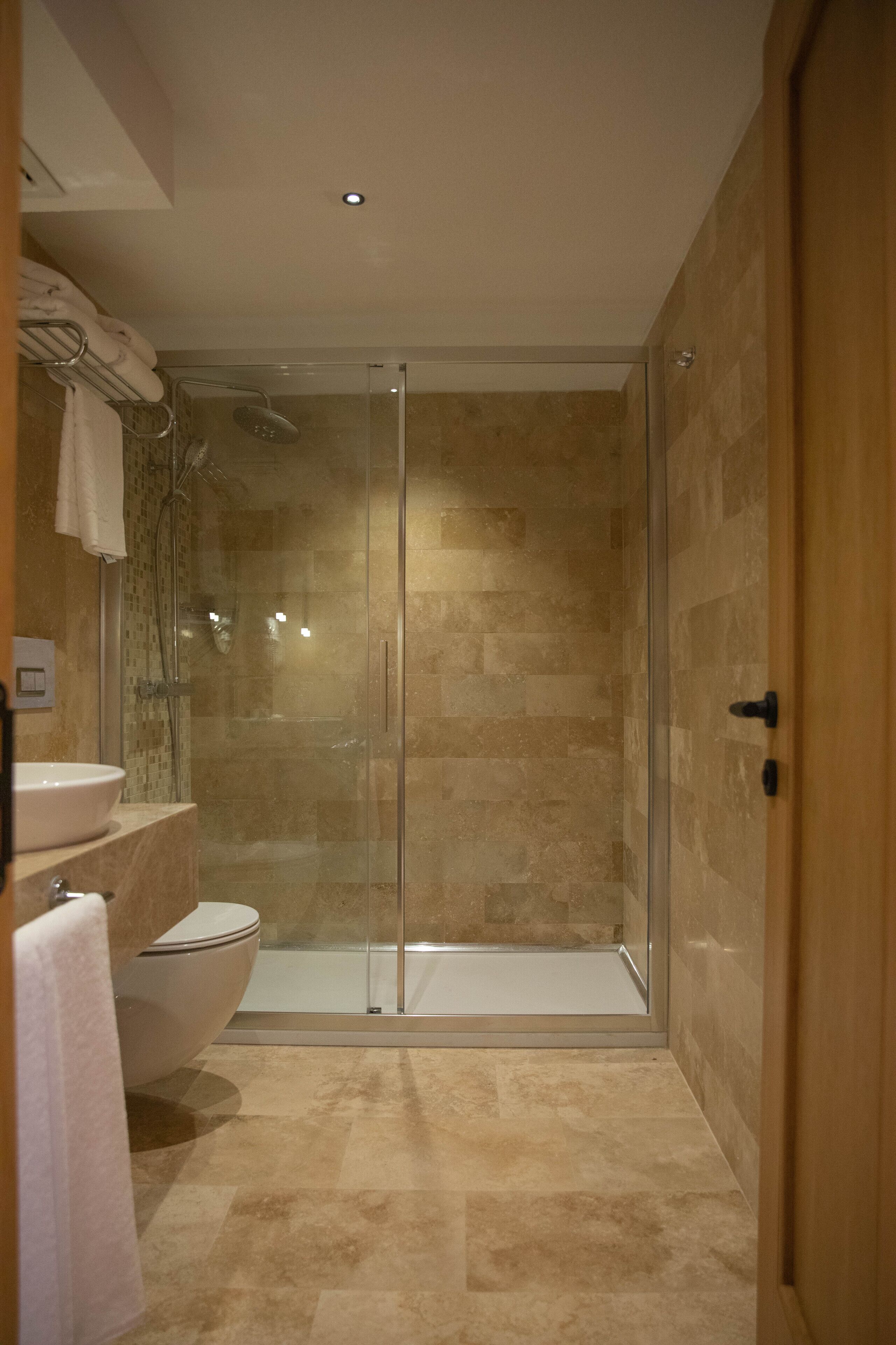 A modern bathroom with a glass-enclosed shower, a toilet, and a sink.