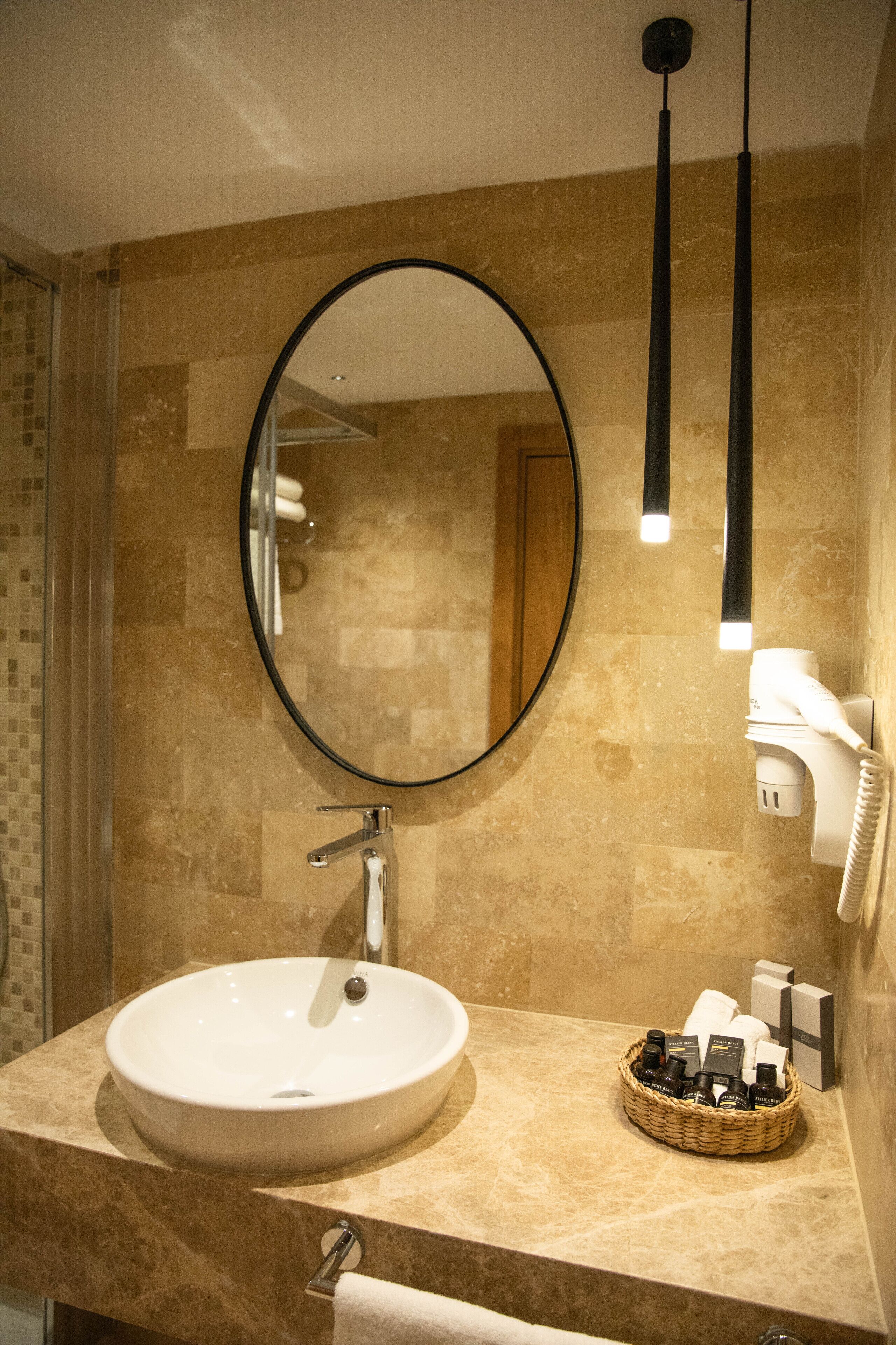 Un baño con un espejo redondo, un lavabo y un perchero para toallas.