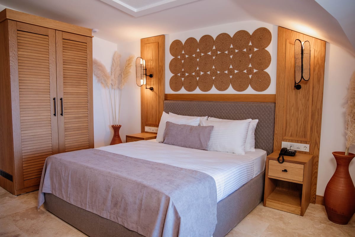 Une chambre à coucher avec un grand lit, une armoire en bois, des tables de chevet et un panneau décoratif mural.