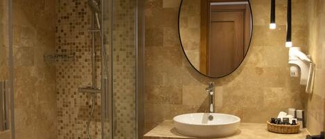Une salle de bain moderne avec une douche à parois de verre, un miroir rond, un lavabo et un porte-serviettes.