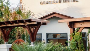 Villa Qua Boutique Hotel with a modern facade, wooden pergola, and lush greenery.