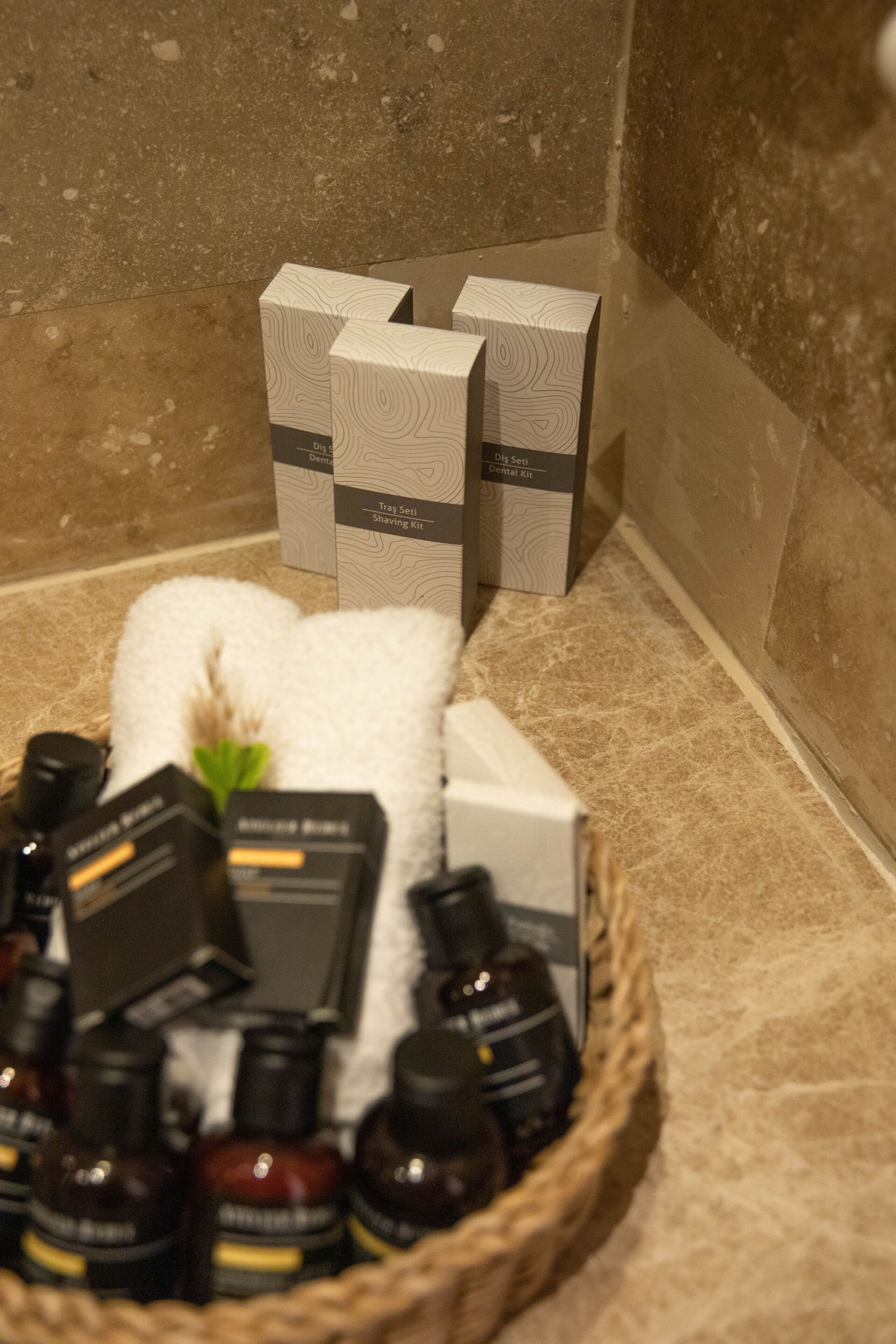 A bathroom with a white towel, a basket of toiletries, and boxes of products on the counter.