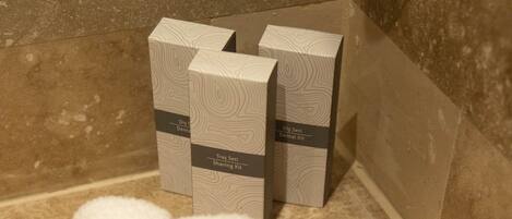 A bathroom with a white towel, a basket of toiletries, and boxes of products on the counter.