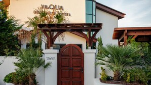 Villa Quia Boutique Hotel with a wooden gate, potted plants, and a white exterior wall.