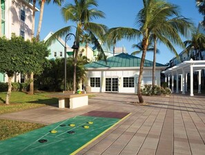 Relax in our serene courtyard, featuring a shuffleboard court, palm trees, and the DESSERT ROOM building with a green roof.