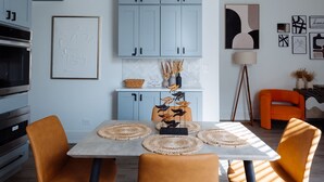Una cocina moderna con armarios azul claro, una mesa de comedor con sillas anaranjadas y una lámpara de pie.